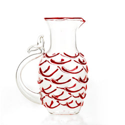 A transparent Murano glass pitcher with red fish-like scales and a fishtail-shaped handle.