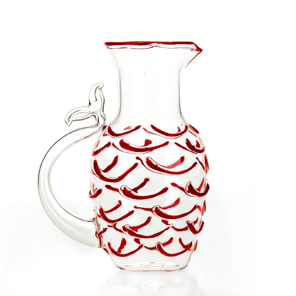 A transparent Murano glass pitcher with red fish-like scales and a fishtail-shaped handle.