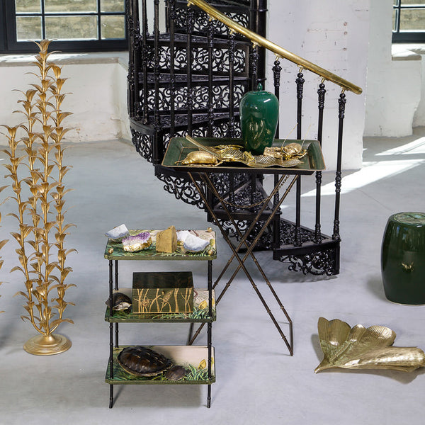Decorative Brass ginkgo leaf styled on a cement floor with other decor objects around