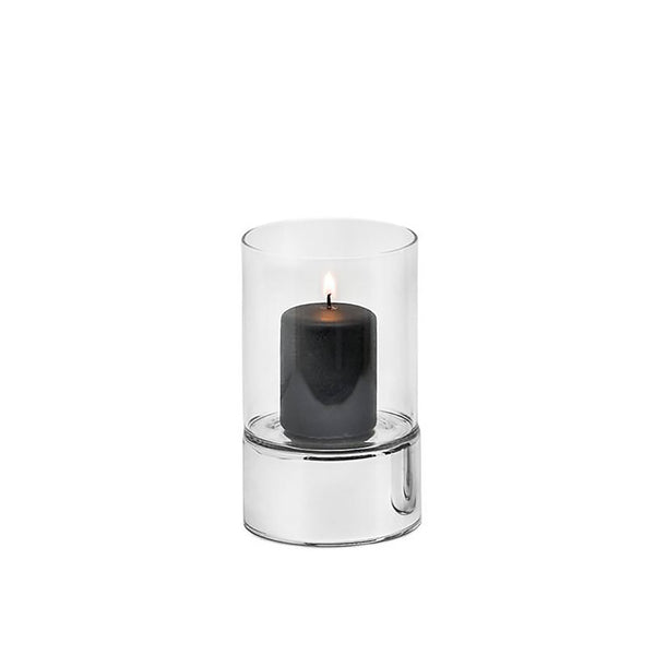 A silver and clear glass hurricane lamp candle holder with a lit candle inside, placed on a flat surface.