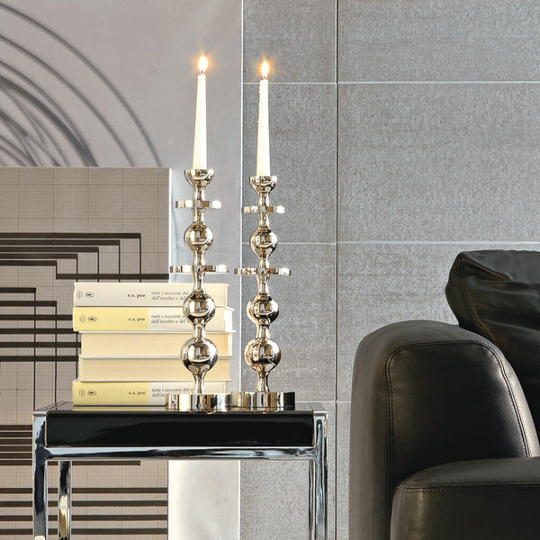 A contemporary style imperial candle holder in platinum ceramic, with two candles, placed on a table in a living room setting.