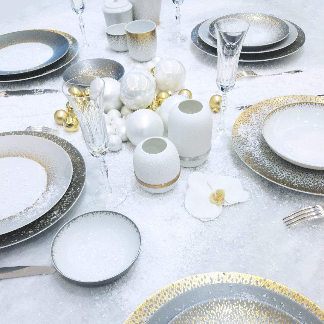 table decorated with white snow effect featuring plates and white candle holder styled with white orchid
