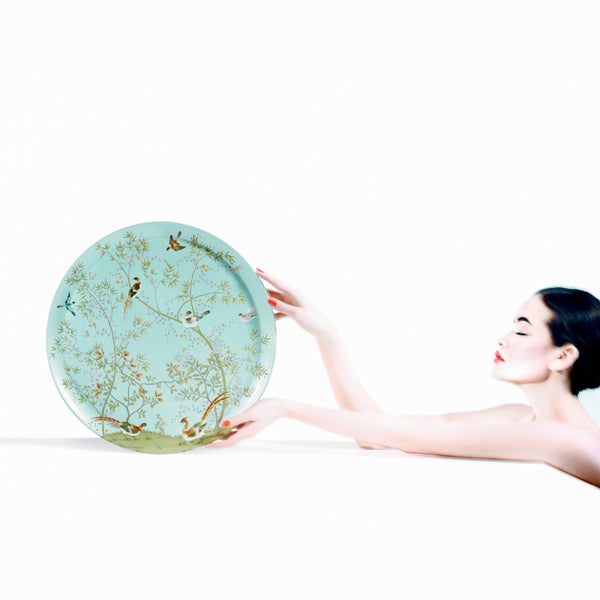 woman holding to a turquoise platter with birds and floral design