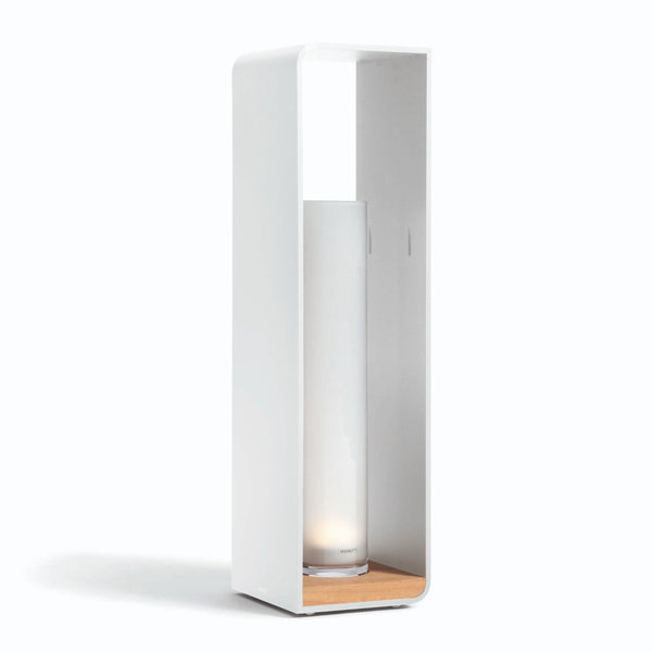 A large rechargeable electric flame lumo outdoor light in white, with a remote control set on a stand, made by Manutti.