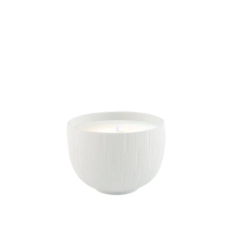 A white porcelain candle holder with a candle inside, on a plain background.