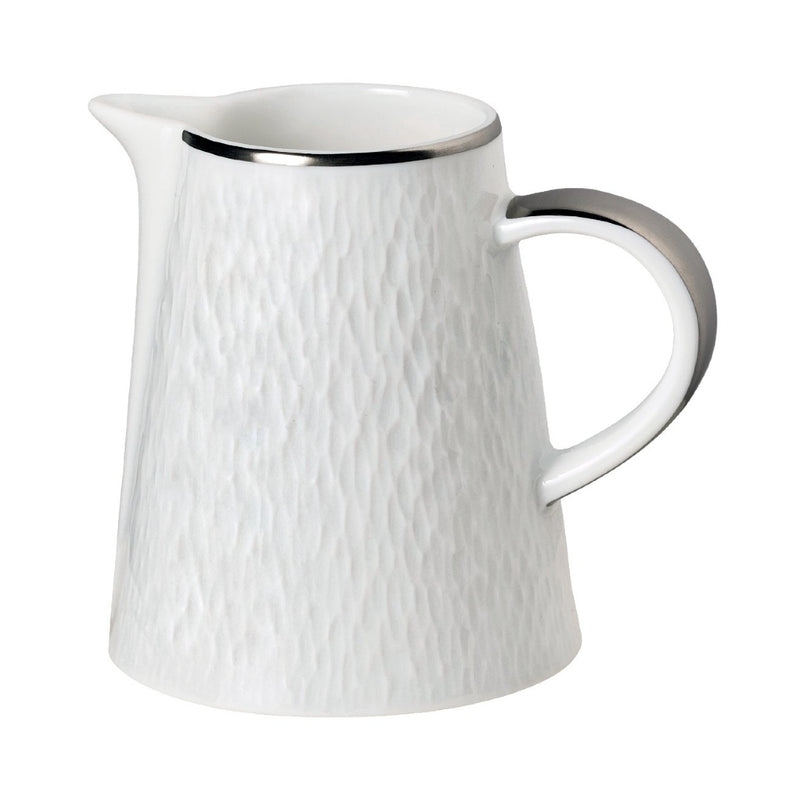 A white porcelain milk jug with platinum detailing on the rim and handle, and a textured surface.