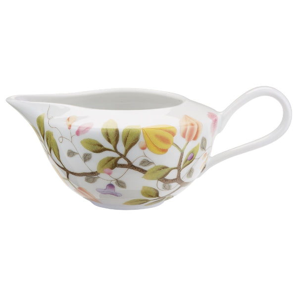 A white porcelain milk jug with green and brown floral patterns and a turquoise rim.