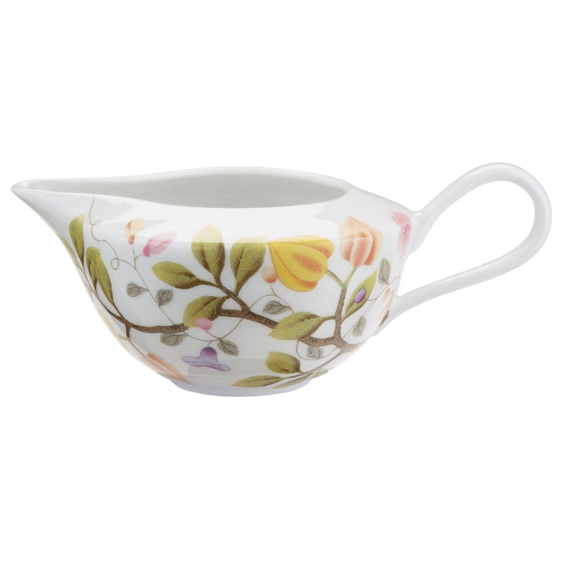A white porcelain milk jug with green and brown floral patterns and a turquoise rim.