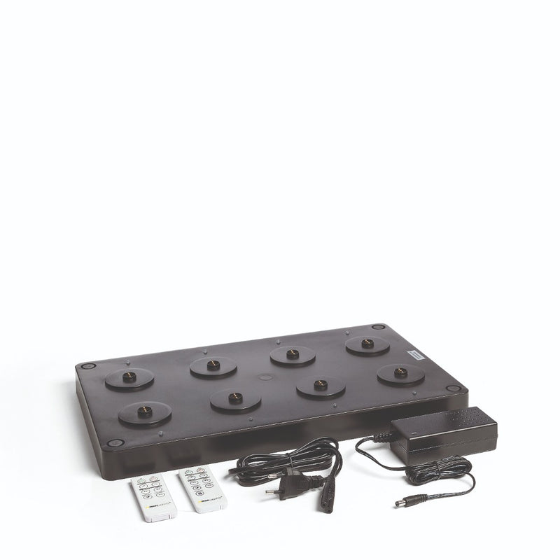 A black multi charger with an EU power plug and two remote controls for Flame Lumo and Sandua Lanterns, against a white background.