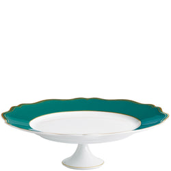 A round, white porcelain cake stand with turquoise and gold accents on the edges, featuring a scalloped and gilded contour.