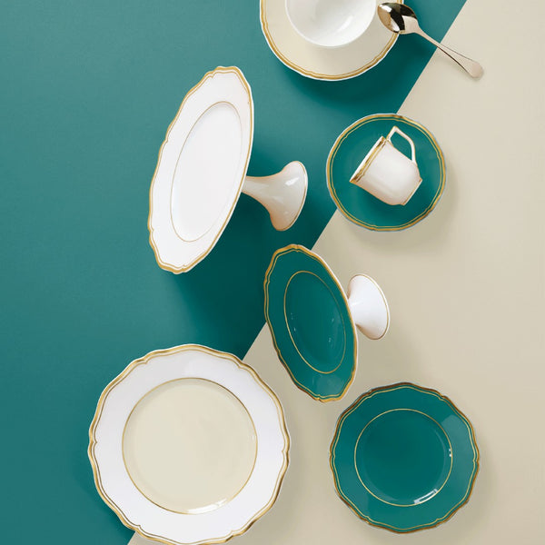 styled  Mazurka Turquoise petit four and cake stand by Raynaud in Limoges porcelain with turquoise glaze, scalloped edge, and gold rim on a white pedestal.
