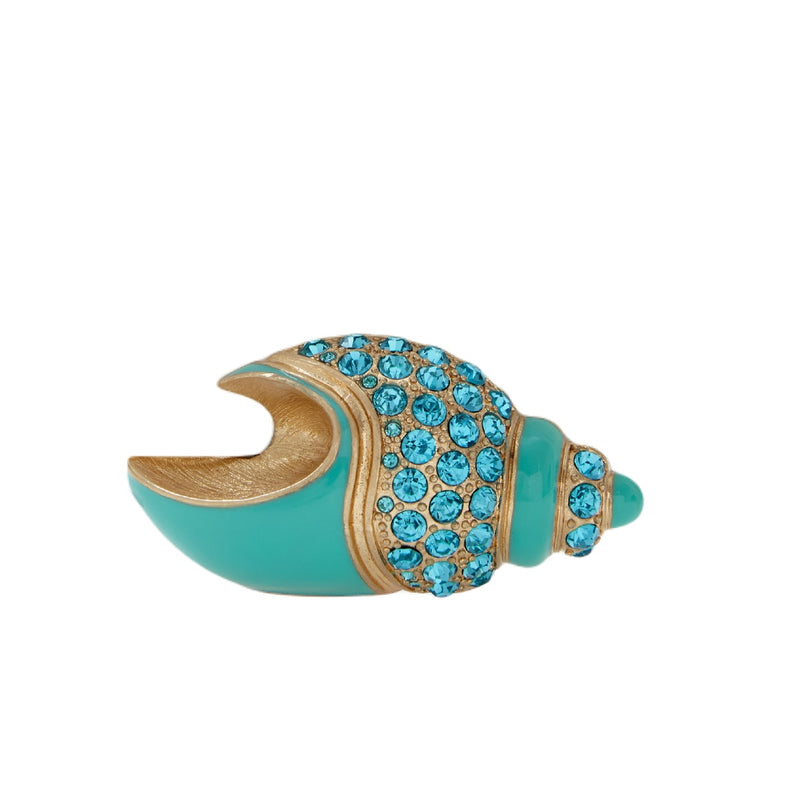 A decorative shell-shaped place card holder with turquoise color and gold accents, adorned with blue gem-like embellishments.