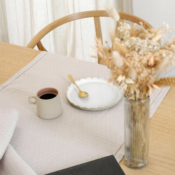 coffee cup styled on a beifge runner and flowers