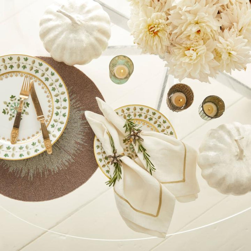 Glass table styled with 2 capiz white pumpkin, cream flowers gold candle holders and white floral plate