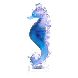 A crystal sculpture of a seahorse in blue and pink colors.