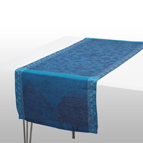 A blue linen table runner with a floral pattern, laid out on a white table.