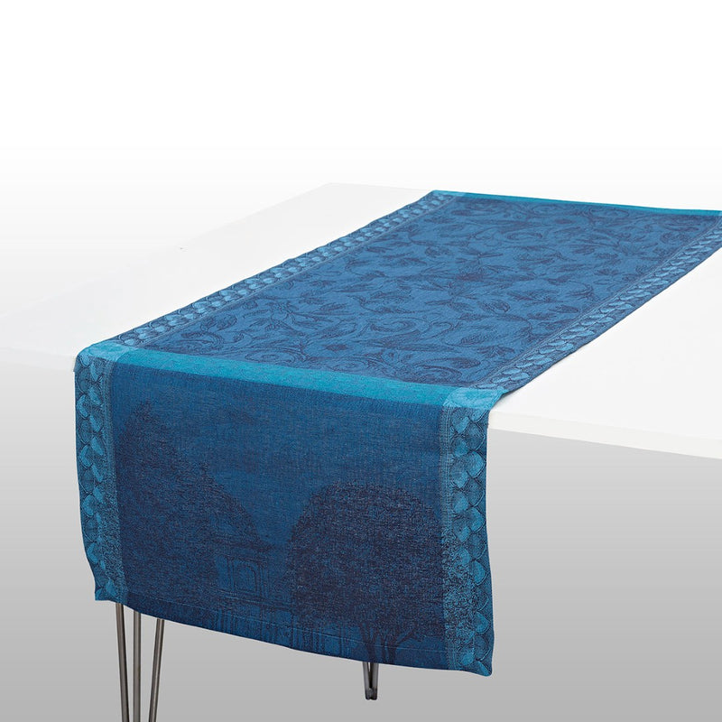 A blue linen table runner with a floral pattern, laid out on a white table.