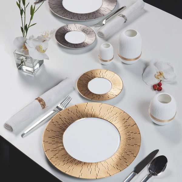 table decorated with white tablecloth, gold and silver plates and orchid flowers
