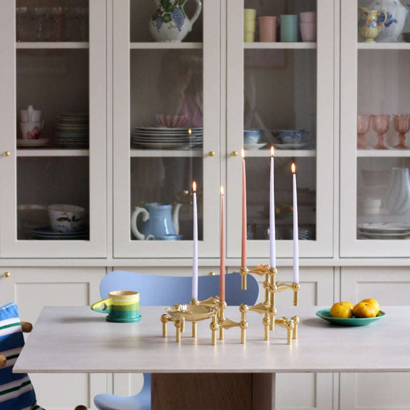 styled kitchen table showing the brass candle holders from Stoff Nagel with crockery cabinet in the background