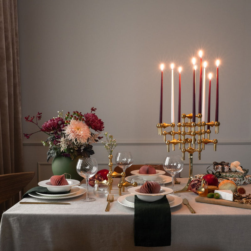 Decorated dining table with candelabra and candles, flowers and plates