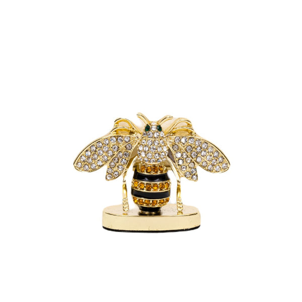 A decorative striped bee place card holder with gold, black, and clear colors, crafted from zinc, enamel, and glass.
