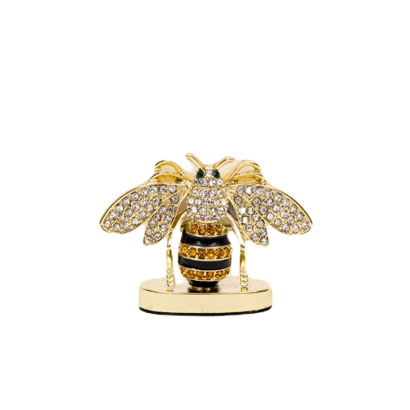 A decorative striped bee place card holder with gold, black, and clear colors, crafted from zinc, enamel, and glass.
