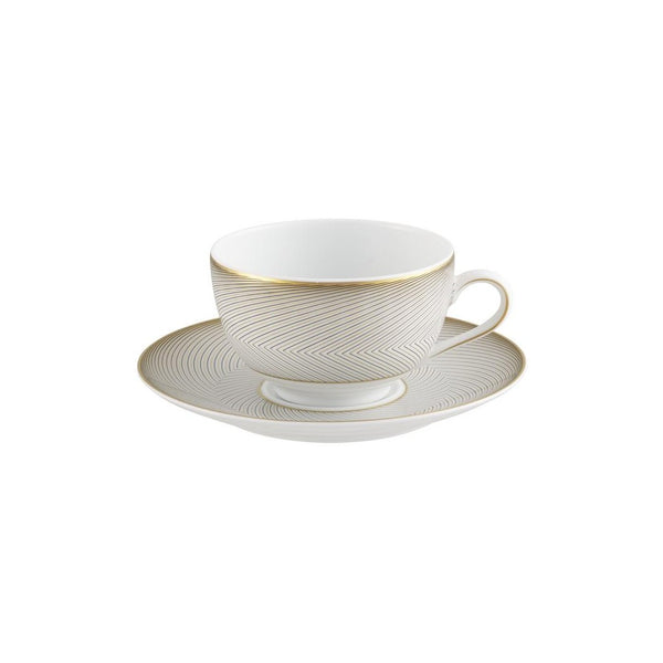 A white porcelain tea cup with gold and black geometric patterns on the cup and saucer, set against a plain background.