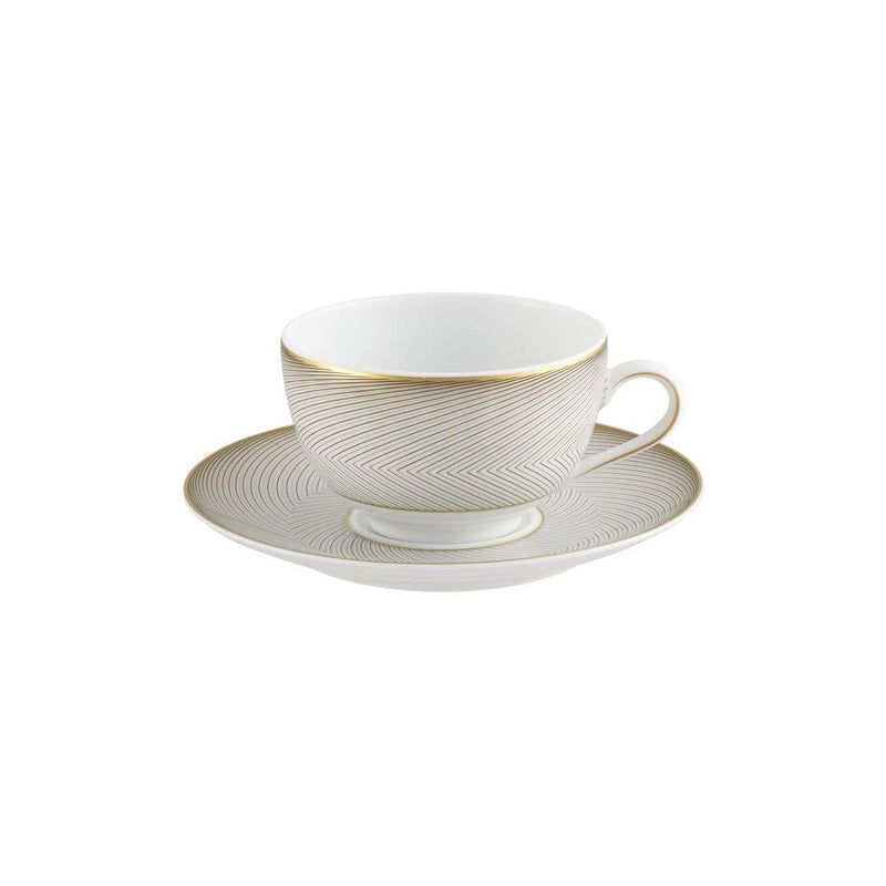 A white porcelain tea cup with gold and black geometric patterns on the cup and saucer, set against a plain background.