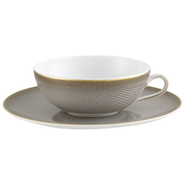 A white porcelain tea cup with black and gold geometric patterns on the cup and saucer, showcasing the Raynaud brand.