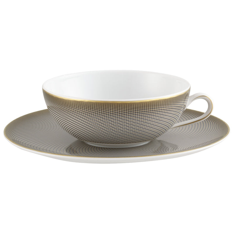 A white porcelain tea cup with black and gold geometric patterns on the cup and saucer, showcasing the Raynaud brand.