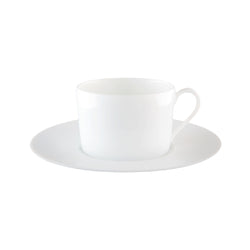 A white porcelain tea cup with a saucer, displaying a counter-relief engraving which is part of the Infini collection by Haviland.