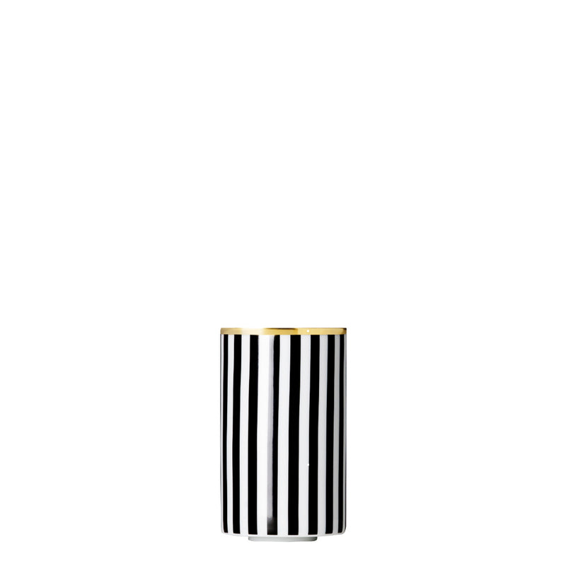 A cylindrical porcelain tea strainer beaker with black and gold stripes and geometric patterns.