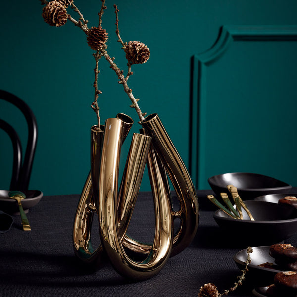 triu gold vase styled with flower against green wall