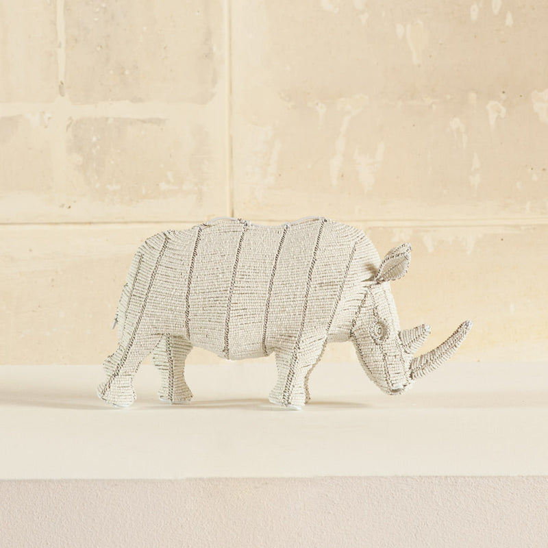 A white beaded rhinoceros sculpture made with traditional wire and glass beads with cream background